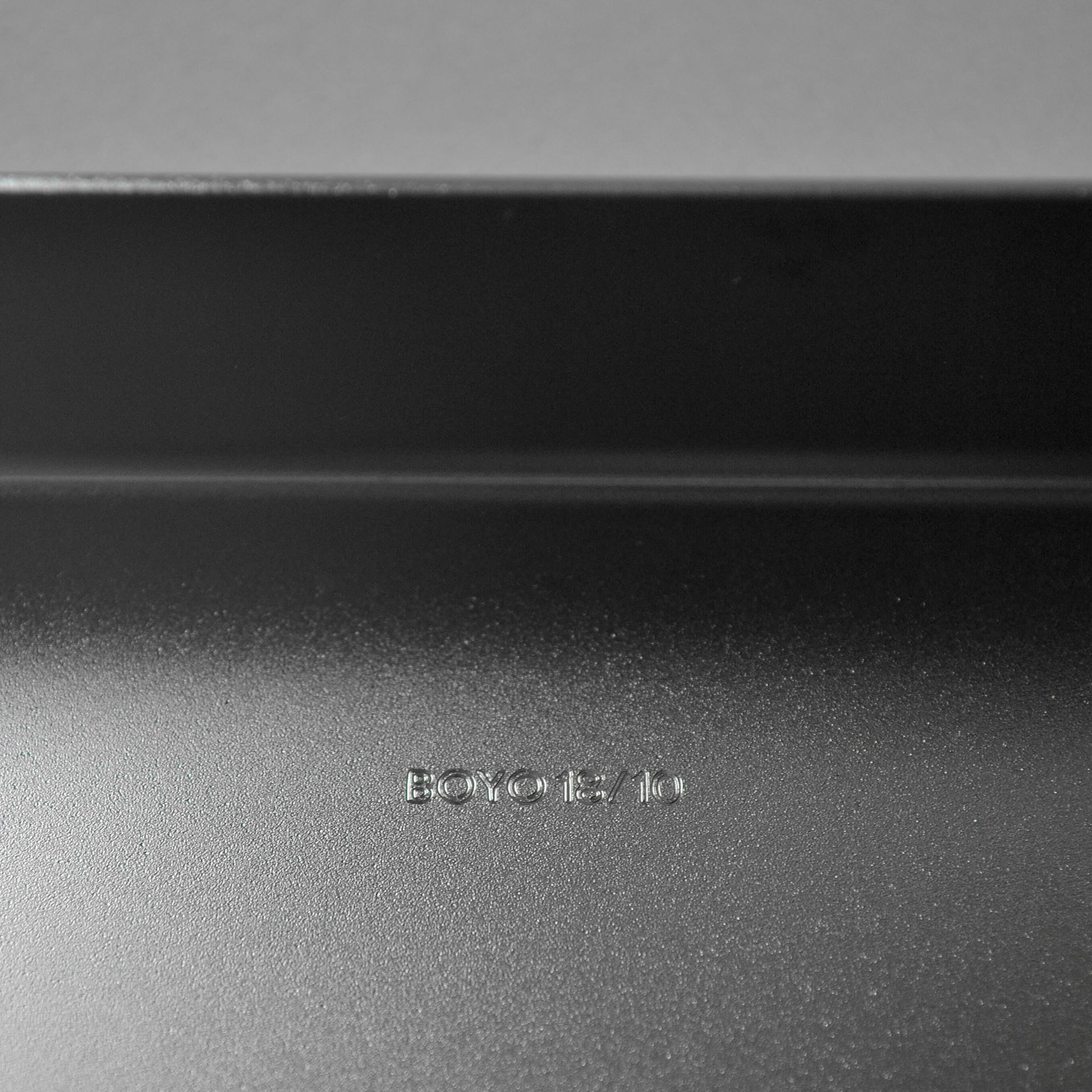 Close-up of logo engraved on a matt stainless steel surface