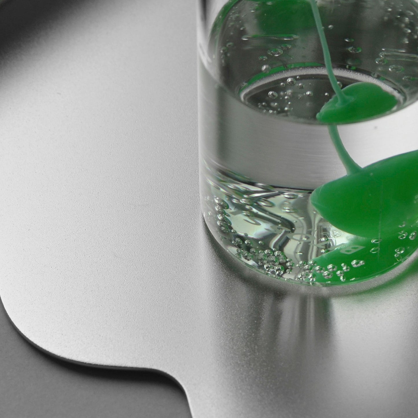 Close-up of a glass ith green cherry in a glass on a modern serving tray in stainless steel