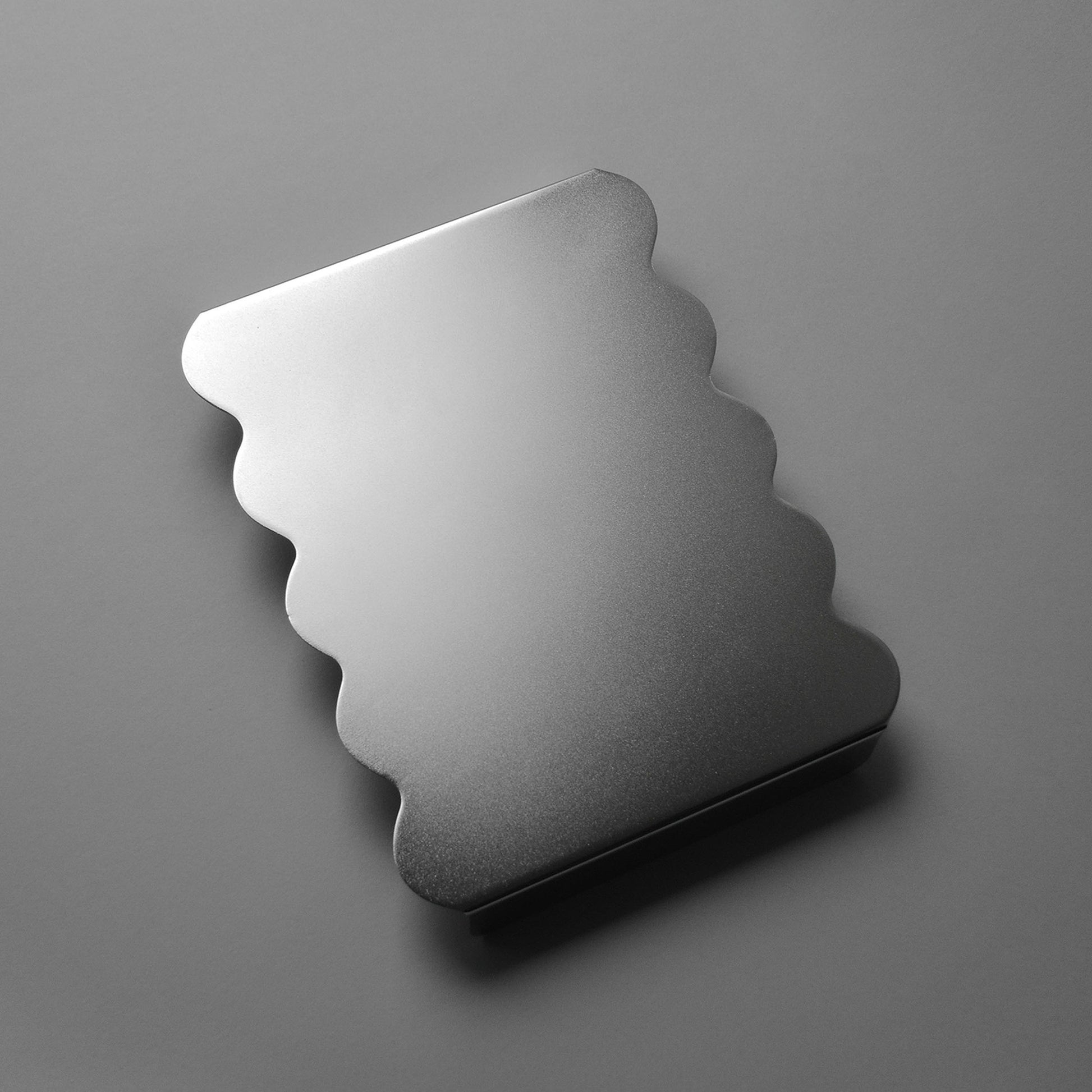 Stainless steel, wavy-shaped serving stand with satin finish on a gray background 