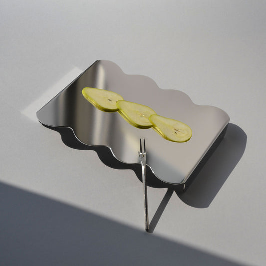 Top view of a modern serving stand with reflective finish and sliced pears on top 