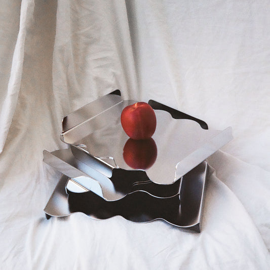 Metallic culptural tarys with a red on a apple white fabric background