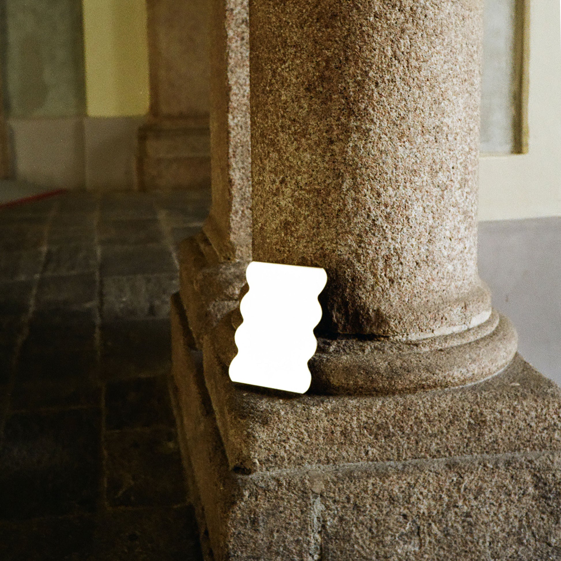 Close-up of a stone column with a sculptural metal serving stand