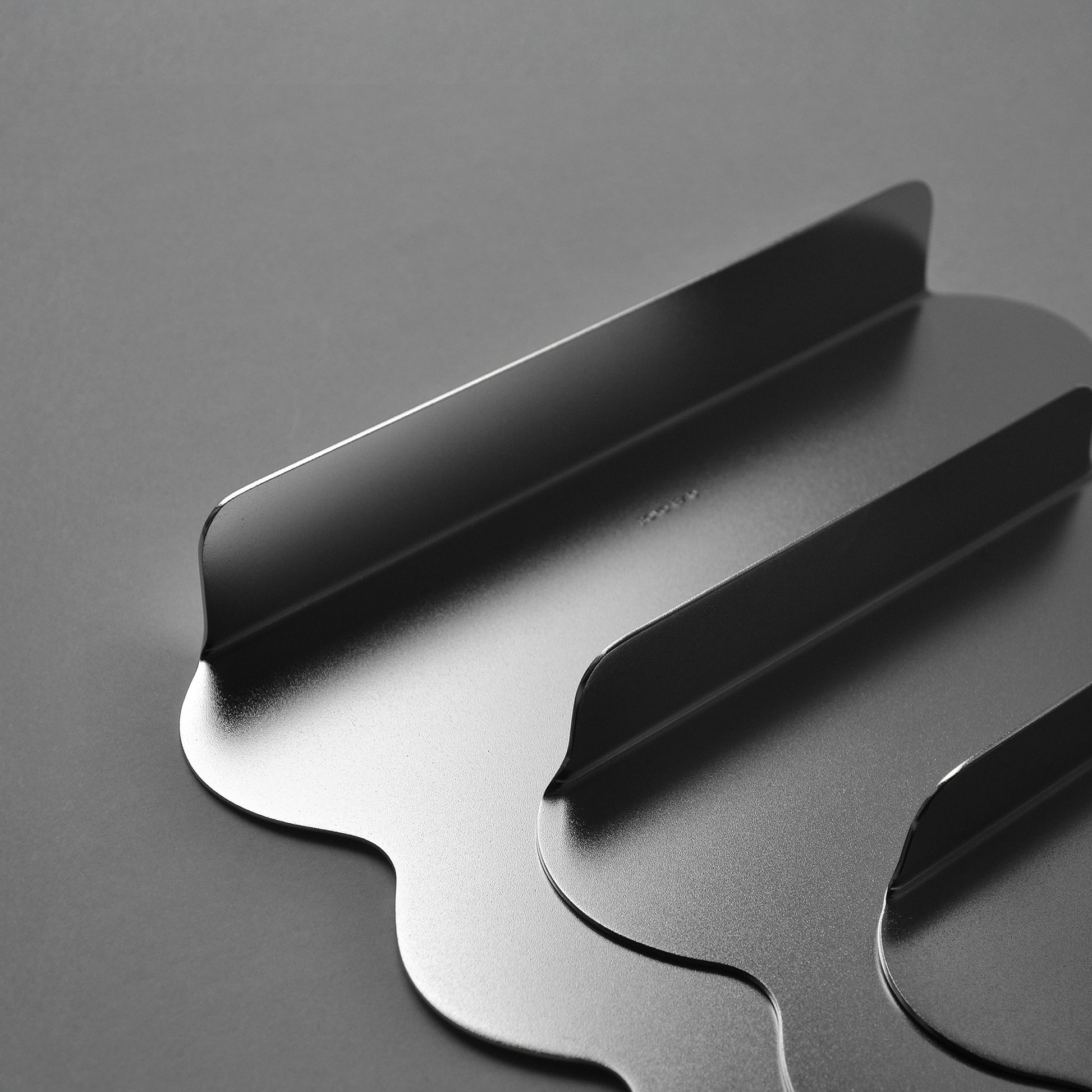 Detail of a set of a sculptural serving trays with wavy edes and matt finish