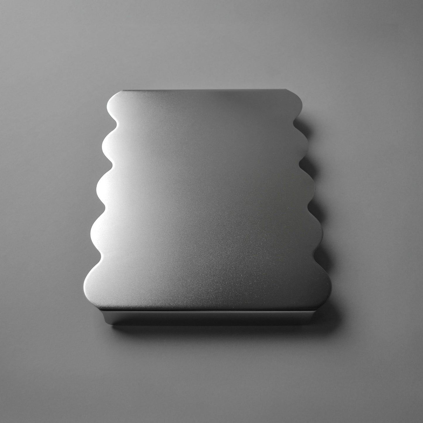 Side view of modern serving stand with sculpted edges in luminous satin finish