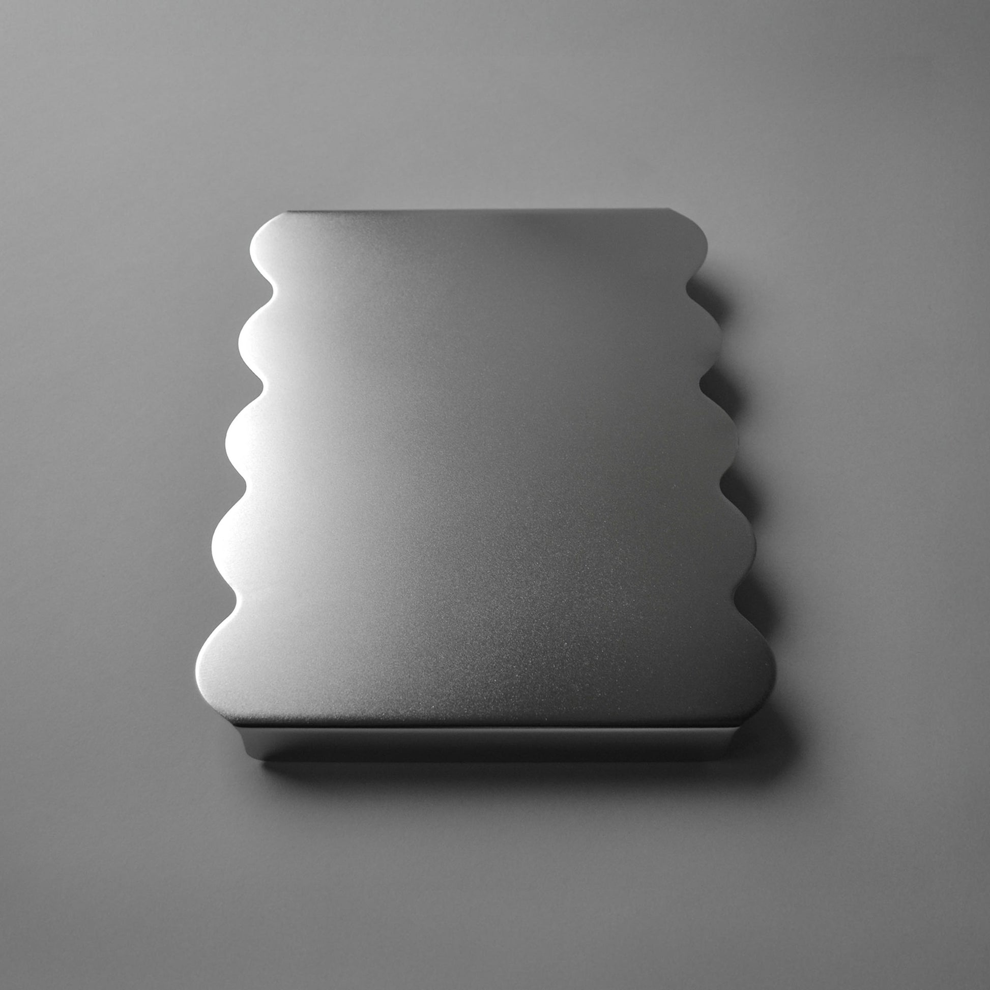 Side view of modern serving stand with sculpted edges in luminous satin finish