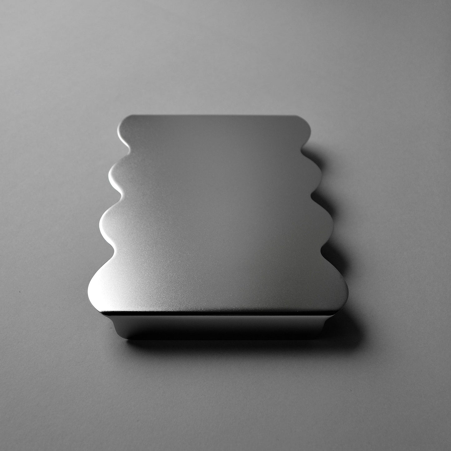 Front view of the modern serving stand with wavy edges in luminous satin finish
