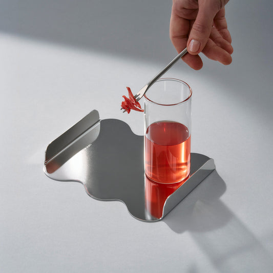 Top view of the sculptural stainless steel tray with red cocktail and sweet petals