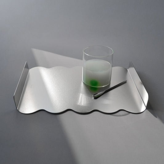 Modern wavy tray in stainless steel with a glass and spoon
